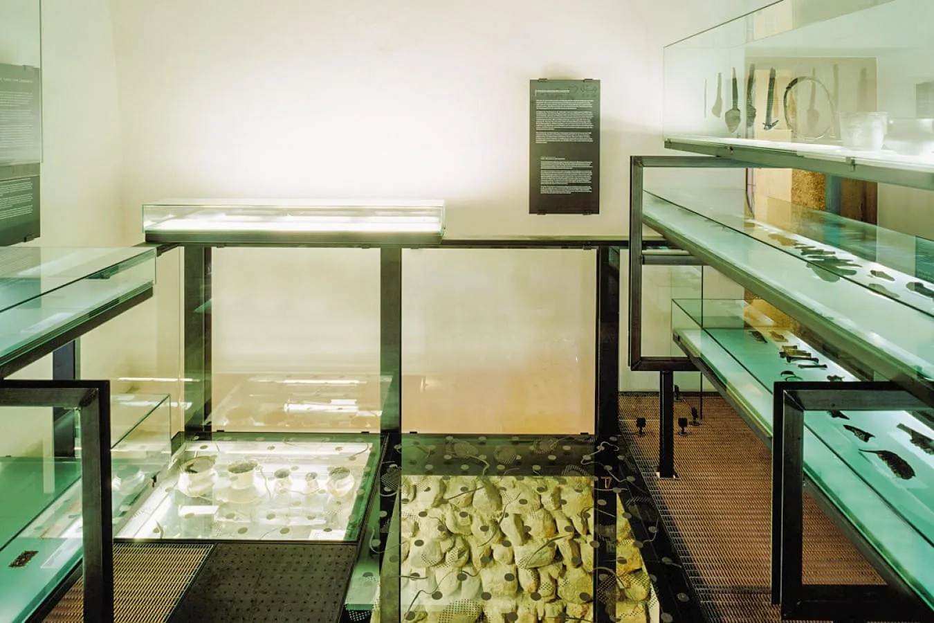Ein Ausstellungsraum im Museum Kitzbühel mit beleuchteten Vitrinen, die archäologische Artefakte zeigen. 